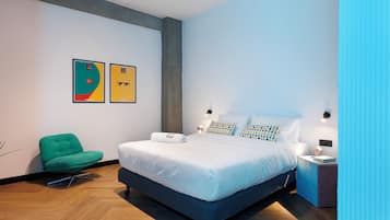 A modern bedroom with a large bed, a green chair, and two framed artworks on the wall.