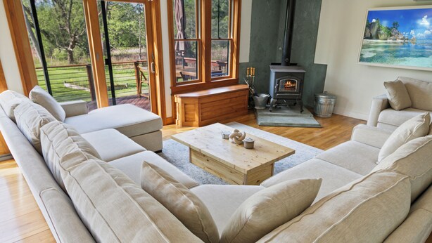 A spacious living room with a large beige sofa, a wooden coffee table, and a fireplace.