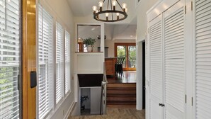 A hallway with a wooden floor, white walls, and a ceiling light fixture. There are white doors on the right and a staircase leading to another level.