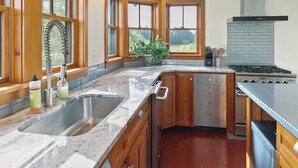 A kitchen with wooden cabinets, a stainless steel sink, a granite countertop, and a gas stove.