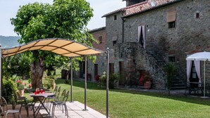 An outdoor patio with a table and chairs, a pergola, and a stone building in the background. - Villa in Cortona with 8 bedrooms sleeps 16 (Cortona)