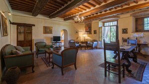 A spacious living room with a high wooden ceiling, comfortable seating, a television, and a bookshelf. - Villa in Cortona with 8 bedrooms sleeps 16 (Cortona)