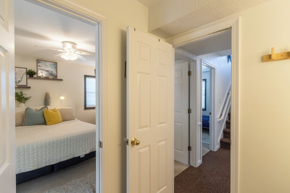 A hallway with a bed, a ceiling fan, and a staircase leading to another room.