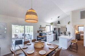 A modern kitchen with white cabinetry, a central island, and a dining area with a wooden table set for four.
