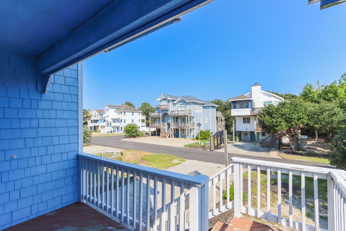 A residential area with a blue house, a white fence, and a clear blue sky.