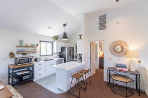 A modern kitchen with white cabinetry, a central island, and bar stools.