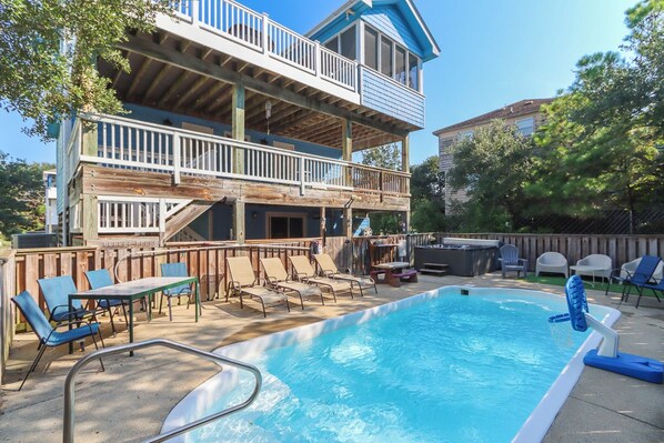 A two-story building with a pool, outdoor seating, and a hot tub.