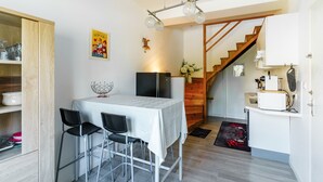 Cocina compacta con mesa, sillas, refrigerador y escalera de madera.