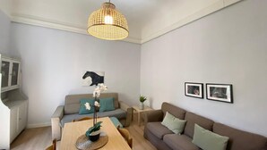 Uma sala de estar moderna com uma mesa de jantar de madeira, dois sofás, um lustre e um armário.