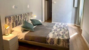 Quarto com cama, mesas de cabeceira e abajur.