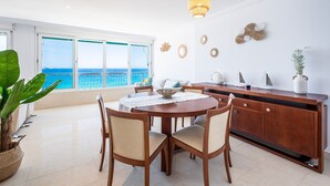 Un comedor moderno con una mesa redonda, sillas y vistas al océano a través de grandes ventanales.