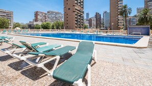 Zona de piscina con sillones de descanso y vista a altos edificios al fondo.