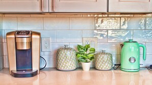 Una encimera de cocina con una cafetera, dos frascos decorativos y un hervidor verde.