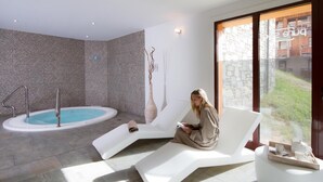 A modern spa room with a hot tub, a lounge chair, and a large window with a view of a stone building. - Wifi, 300m from shops, view mountain, swimming pool, sauna, hammam, terrace, balcony, tv, ski locker (Montgenèvre)