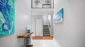 Ein moderner Flur mit einer Treppe, einem Holztisch mit Lampe und zwei Bildern an den Wänden.
