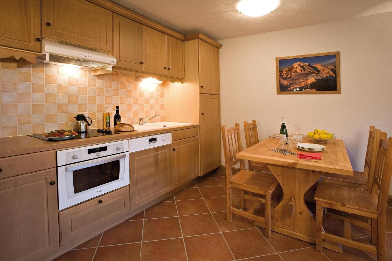 A kitchen with wooden cabinets, a tiled backsplash, a stove, and a dining table with chairs.