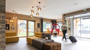 A modern lobby with a large sofa, a red seating area, and a suitcase on the floor. - Wifi, swimming pool, terrace, balcony, tv, ski locker, 47-51m², Samoëns (Samoëns)