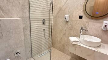 A modern bathroom with a glass-enclosed shower, a sink with a mirror, and a toilet.
