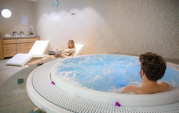 A spa room with a hot tub, a wooden cabinet, and a clock on the wall.