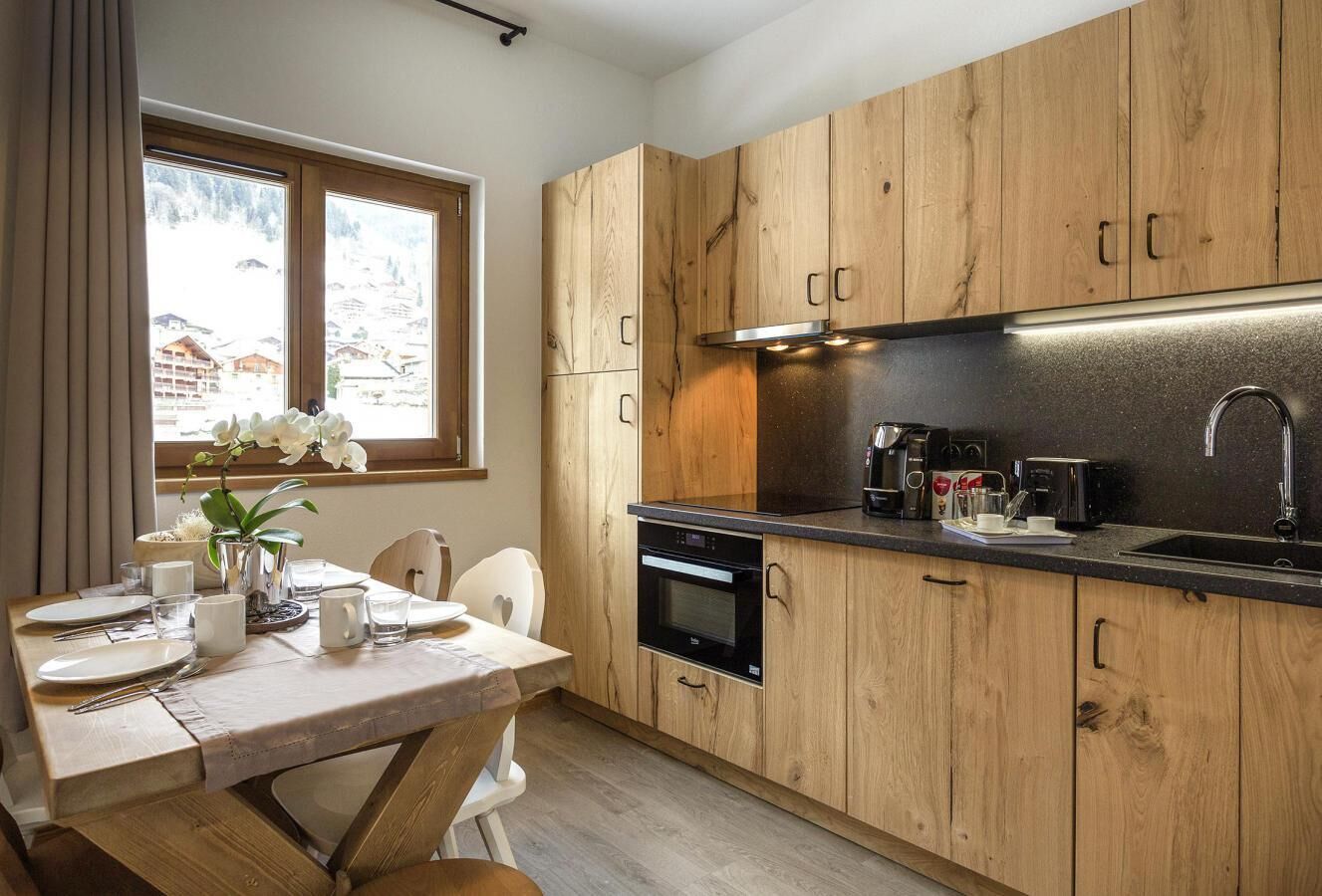 A modern kitchen with wooden cabinets, a black countertop, and a built-in oven.