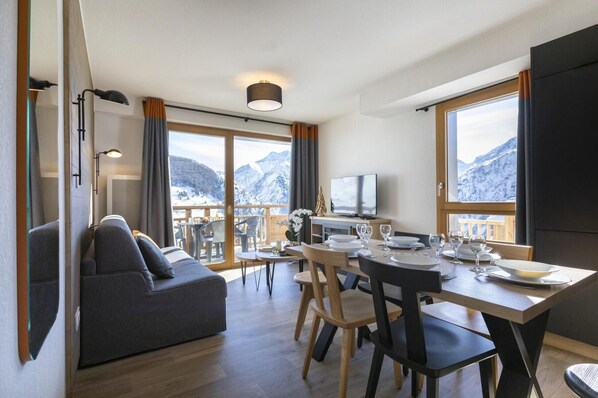 Relax in a spacious room with a seating area, dining table, and large windows offering breathtaking mountain views.