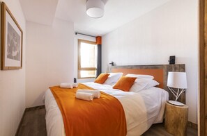 Cozy retreat with a neatly made bed, bedside table, and framed picture.
