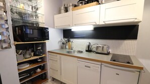 Cocina pequeña con armarios blancos, microondas, tostadora y lavamanos.