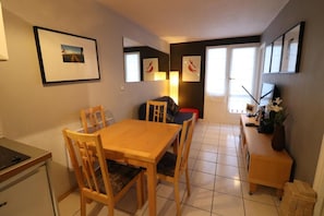 A compact dining area with a wooden table and chairs, a small kitchenette, and a TV on a stand. - 100m from ski slopes, 4th floor, balcony, tv, ski locker, 30m², Tignes (Tignes)