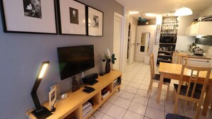 Una sala de estar moderna con televisor de pantalla plana, mueble de madera para entretenimiento y comedor con mesa y sillas.