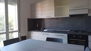 Ett modernt kök med ett stort fönster, en gasspis och ett matbord.