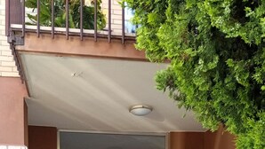 En grind leder in till en byggnad med en fasad av sten och en dörr med ett nummer.
