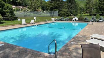 A rectangular swimming pool with clear blue water, surrounded by a brick deck. There are lounge chairs and a fenced area with a 'No Diving' sign.