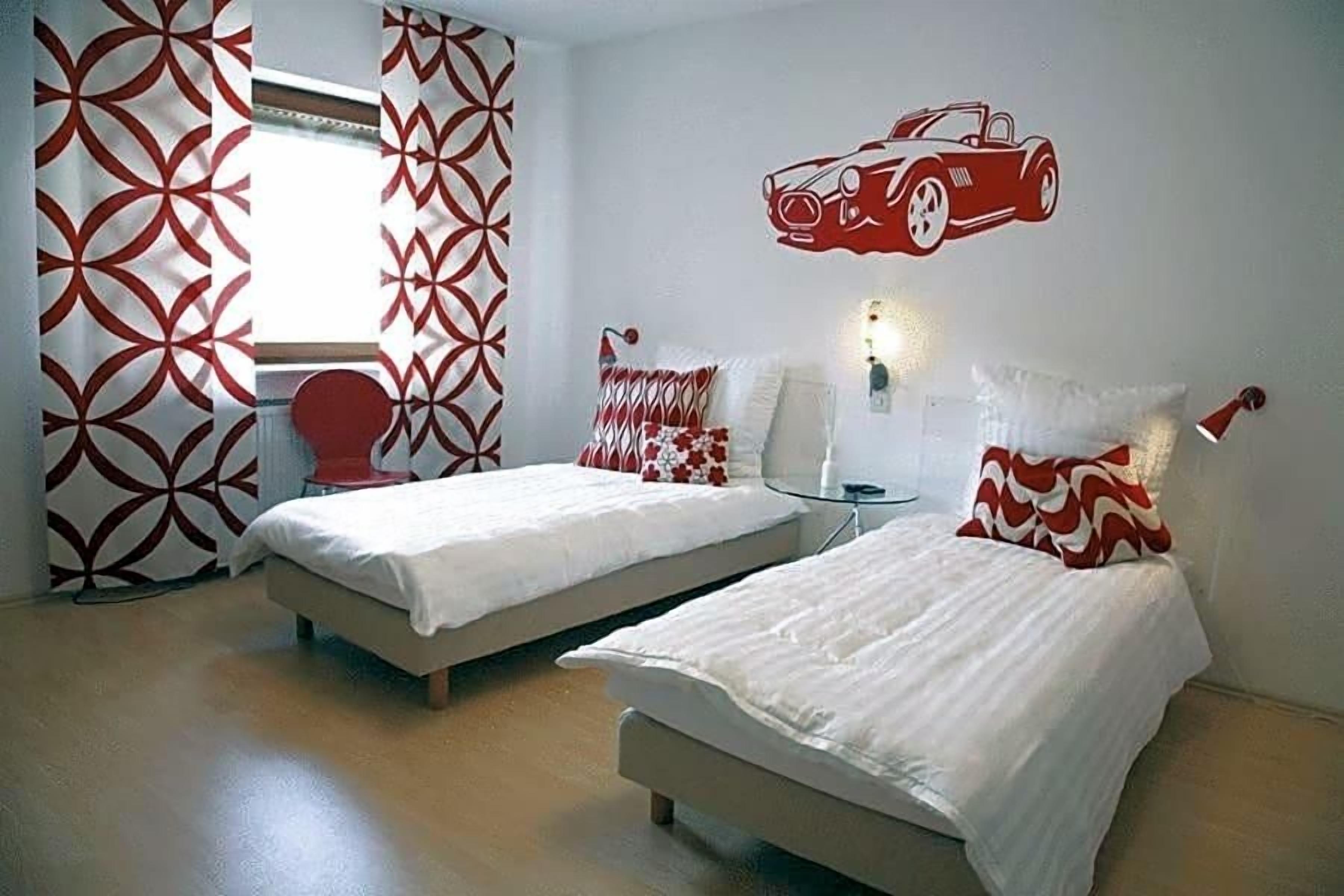 Ein Hotelzimmer mit zwei Betten, einer roten Auto-Wandsticker und einem Vorhangfenster.