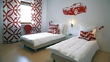 Ein Hotelzimmer mit zwei Betten, einer roten Auto-Wandsticker und einem Vorhangfenster.