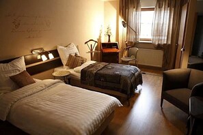 A hotel room with a bed, bedside table, chair, and a small table with a lamp. - Art Hotel Sonnenhof (Hanau)