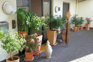 A hotel entrance with potted plants and a stone statue. - Art Hotel Sonnenhof (Hanau)