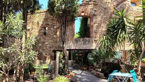 A courtyard with stone walls, potted plants, and outdoor furniture. - Chambres d'hôtes Peu del Causse SPA (Sainte-Colombe-de-la-Commanderie)