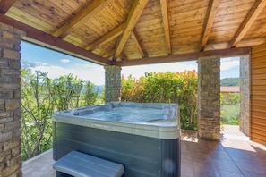 A hot tub under a wooden roof with stone pillars, surrounded by greenery and a view of the landscape. - Villa Dol- a Traditional Istrian house with swimming pool, jacuzzi and sauna (Buzet)