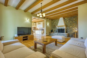 A living room with a TV, sofas, a coffee table, wooden beams, and a stone fireplace. - Villa Dol- a Traditional Istrian house with swimming pool, jacuzzi and sauna (Buzet)