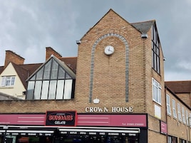 Un bâtiment dont la façade est ornée d’une horloge, avec une enseigne indiquant « Crown House », et un magasin de glaces appelé « Sundays Gelato » situé en dessous.