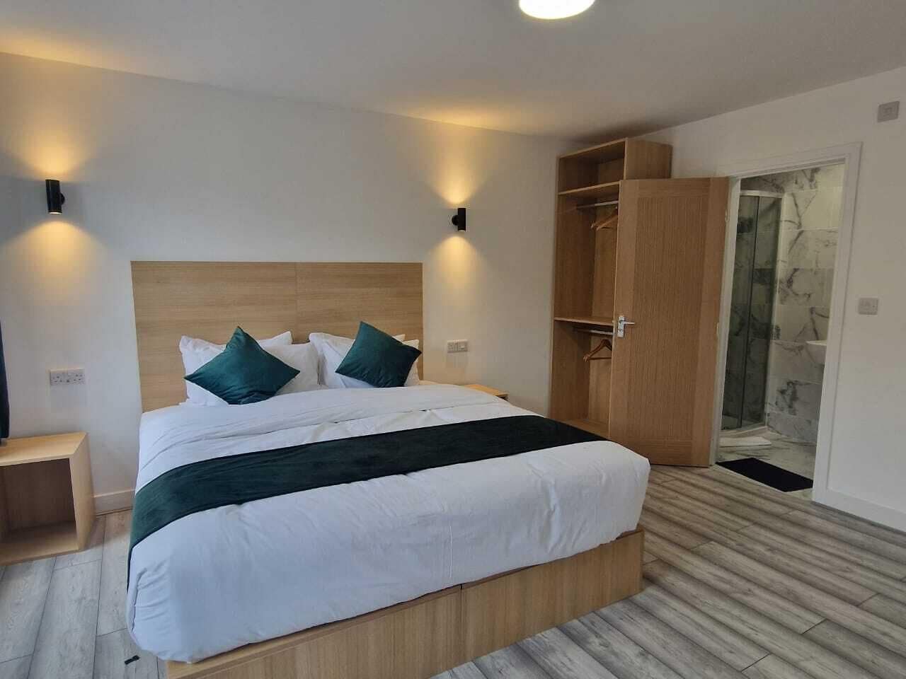 Une chambre moderne avec un grand lit, une tête de lit en bois et deux lampes fixées au mur.