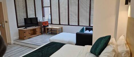 Una habitación de hotel con una cama grande, televisión, un armario de madera y una pequeña mesa.