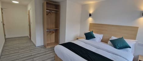 A hotel room with a wooden bed, a walk-in closet, and a hallway.