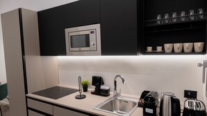A modern kitchen with a built-in microwave, a sink, and a coffee maker. - 2 Bedroom Apartment in Taranto (Taranto)
