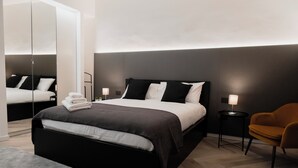 A modern bedroom with a large bed, bedside tables, a chair, and a mirror. - 2 Bedroom Apartment in Taranto (Taranto)