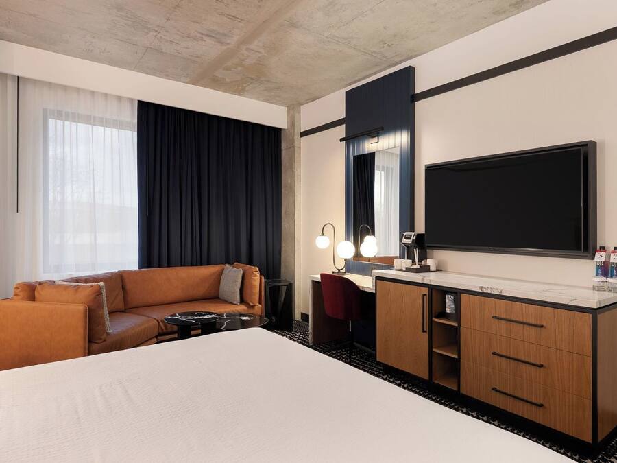 Een hotelkamer met een groot bed, een bank, een bureau met spiegel en een televisie.