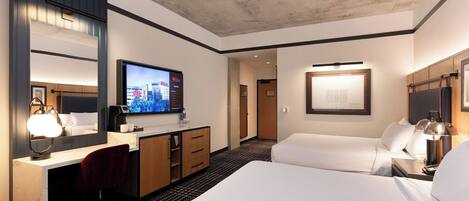 A hotel room with a large bed, a desk with a computer, a television, and a mirror.