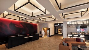 A modern hotel lobby with a reception desk, a large red abstract mural, a herringbone wood floor, a seating area with a sofa and chairs, and a bar with a high counter. - The Rose Gaming Resort (Dumfries)