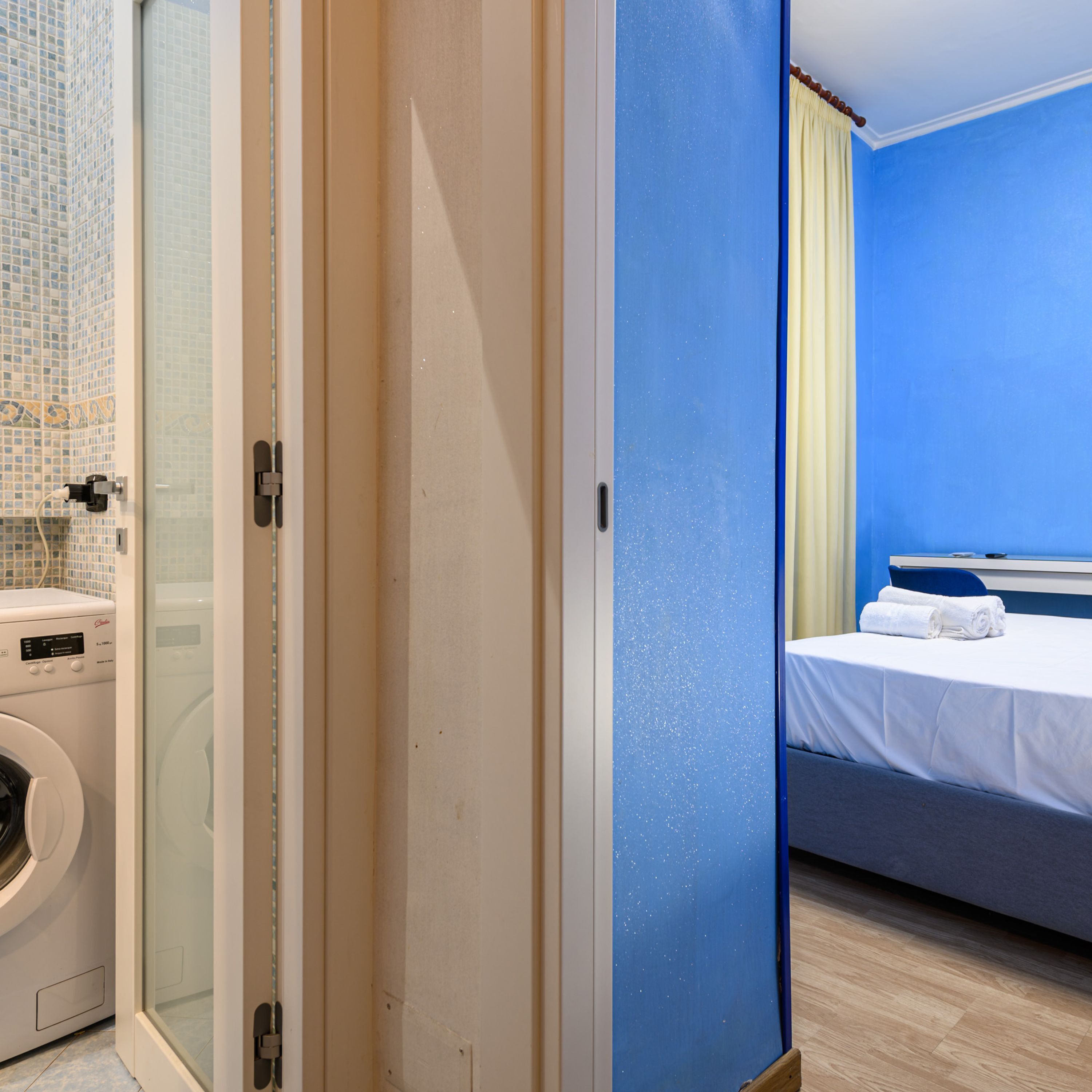 A hotel room with a bed, a washing machine, and a shower area.