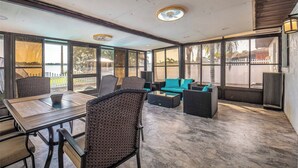 Amplia zona de patio con mesa y sillas, un sofá y un ventanal con vistas al exterior.